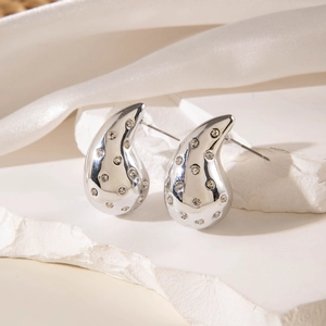 Macro shot of silver teardrop earrings with crystals on a white marble background
