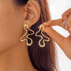 Close-up of gold irregular wavy earrings with a polished metallic finish on a model
