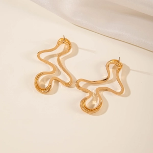 Close-up of golden irregular wavy earrings with a polished metallic finish on silk