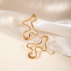 Detailed view of golden irregular geometric hollow stud earrings on white satin