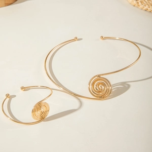 Detailed view of a gold spiral vortex pendant necklace and matching bangle jewelry set