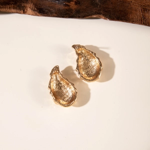 Detailed view of golden teardrop earrings with elegant brushed metal texture and stripes