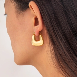 Close-up of a model wearing a polished gold U-shaped geometric huggie hoop earring
