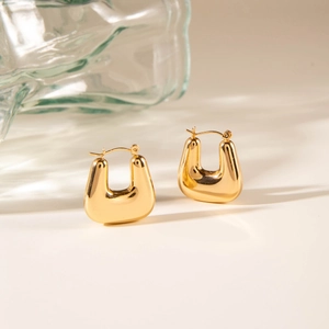 Detailed view of high-polished gold U-shaped hoop earrings on a minimalist background