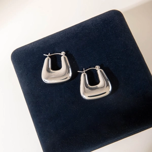 Close-up of silver U-shaped chunky hoop earrings with high polish on blue velvet