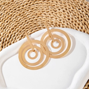 Macro view of gold geometric layered round earrings on a stylish white plaster tray