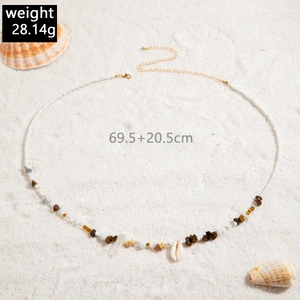 Detailed beach belly chain with white beads, sea shells and turquoise on sand background