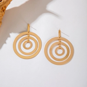 Macro detail of gold geometric triple-ring earrings on textured paper surface