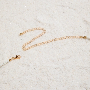 Detailed view of white seed bead waist chain with gold lobster clasp and extension link