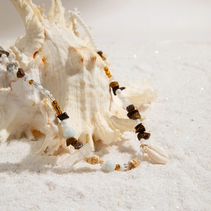 Bohemian beach waist chain with sea shells, blue beads and stones on white sand background