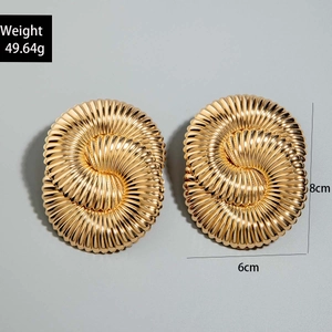 Detail view of large gold spiral geometric earrings with striped texture and dimensions