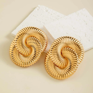 Macro shot of large golden double-ring twist earrings with elegant spiral metal texture