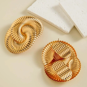 Macro shot of large golden geometric earrings with spiral folded texture and glossy finish