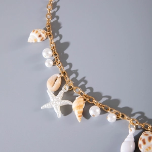 Detailed close-up of beach style body chain with starfish, seashells and white pearls