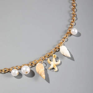 Detail of beach waist chain with starfish, shell pendants and white pearls on gold chain