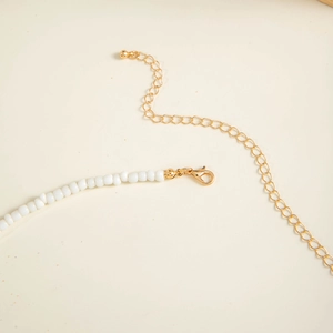 Detail of beaded beach waist chain with golden lobster clasp and adjustable extension link