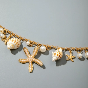 Macro detail of gold seaside jewelry set with starfish, seashell charms and white pearls