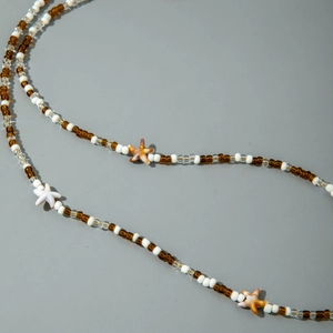 Close-up of beach style beaded body chain with small starfish charms on grey background