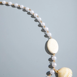 Detail of bohemian pearl necklace with marble stone and natural shell pendant