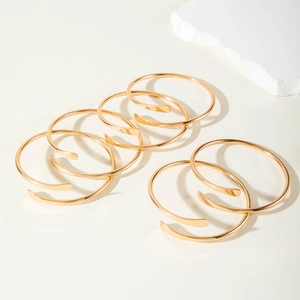 6er-Set goldene Spiral-Armreifen mit poliertem Finish auf minimalistischem Grund