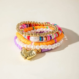 Dettaglio ravvicinato di un ciondolo a cuore su un bracciale multistrato con perline colorate