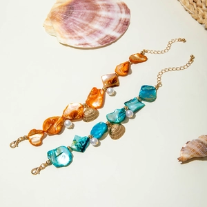 Detail of ocean-themed bracelets with shell fragments, pearls and gold starfish charms