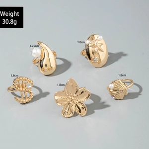 Draufsicht auf ein fünfteiliges Gold-Ring-Set mit Perlen und floralen Akzenten