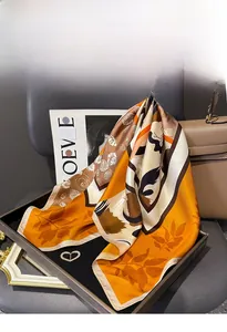 Detailed texture of silk twill square scarf with orange floral pattern and geometric design