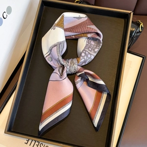 Elegant silk twilly scarf with purple and orange floral prints on a display tray