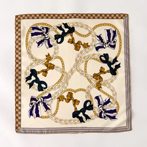 Elegant silk square scarf with golden chain patterns and colorful bows on cream background