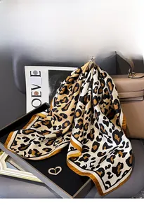 Detail of leopard print silk scarf with heart-shaped buckle on luxury leather bag