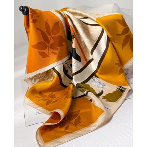 Silky twill square scarf with orange floral pattern draped over minimalist magazine