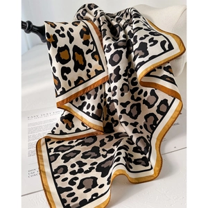 Classic silk leopard print scarf with golden borders draped on a white mannequin