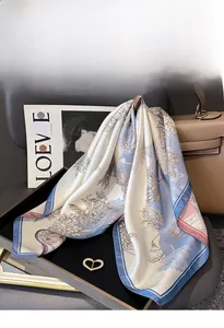 Detail of silk twill floral scarf draped on a luxury bag with soft blue and beige hues
