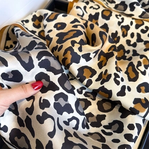 Close-up of leopard print silk scarf showing satin texture and yellow hemmed edges