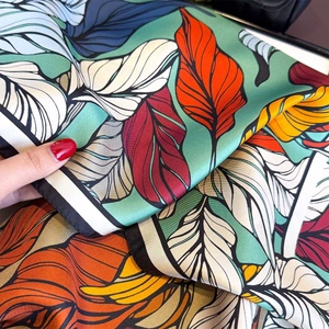 Close-up of premium silk scarf with vibrant leaf prints and fine hand-rolled edges