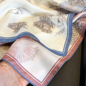 Detail of floral silk scarf showing soft texture and fine rolled edges on wood background