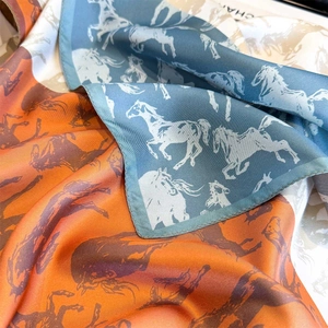 Detailed macro view of vibrant horse print on premium orange and blue silk scarf texture