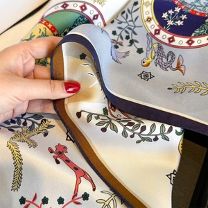Macro detail of hand-rolled edges on a colorful silk twill scarf with mythical prints