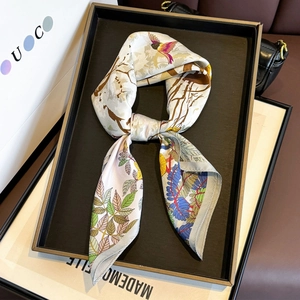 Square silk scarf with floral and bird print displayed on a premium display tray