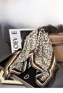 Close-up of leopard print silk scarf with striped edges and gold heart brooch