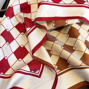 Detail of luxury silk scarf showing twill texture and classic red geometric plaid pattern