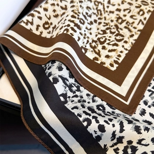 Close-up of leopard print silk scarf showing hemmed edges and smooth fabric texture