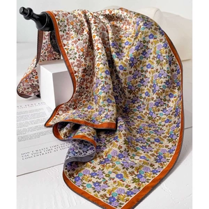 Foulard en soie à fleurs avec ourlet orange et texture sergé sur support de présentation