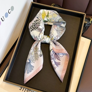 Silk scarf with vibrant floral and bird patterns displayed on an elegant tray background
