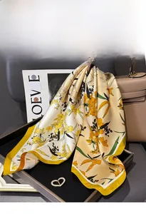Close-up of a floral silk twill scarf elegantly draped over a luxury handbag and gift tray