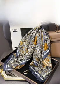 Detail of silk square scarf with paisley pattern folded in a tray with accessories