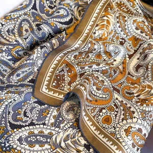 Macro detail of silk paisley scarf showing intricate patterns and premium texture