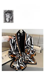 Detail van een zijden sjaal met zebraprint en oranje randen op een luxe bank