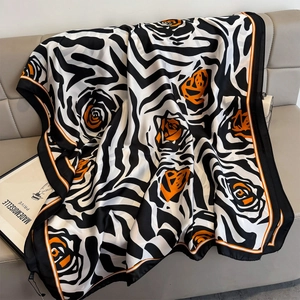 Zijdeachtige sjaal met zebra- en bloemenprint, zwart en oranje, gedrapeerd op bank